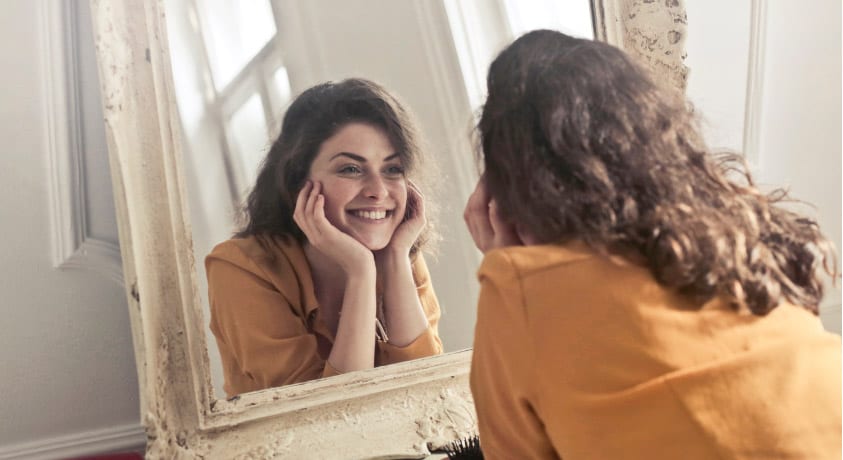 girl smiling into a mirror after successful professional teeth whitening