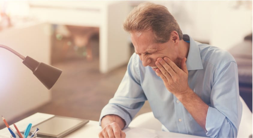 man holding his jaw with phantom tooth pain